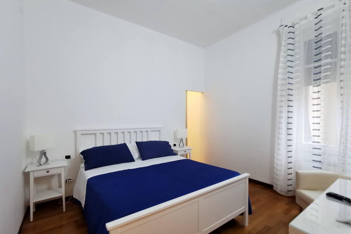 Un dormitorio con cama, mesitas de noche, un escritorio y una silla.