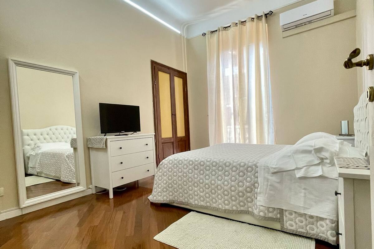 Un dormitorio con cama, cómoda, televisor y espejo.