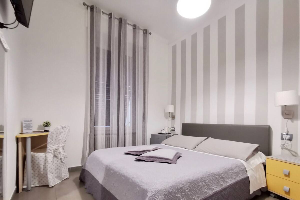 Un dormitorio ordenado con cama, mesitas de noche, escritorio y silla.