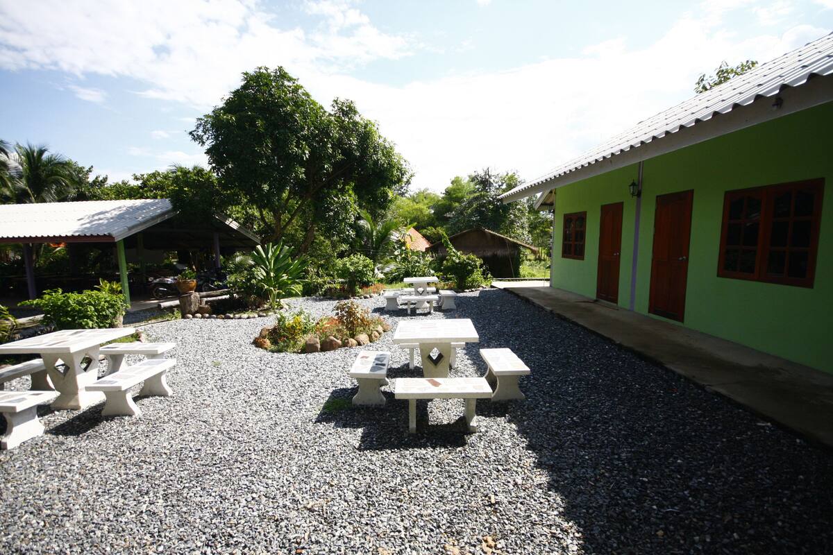 Un patio con mobiliario exterior y un edificio verde.