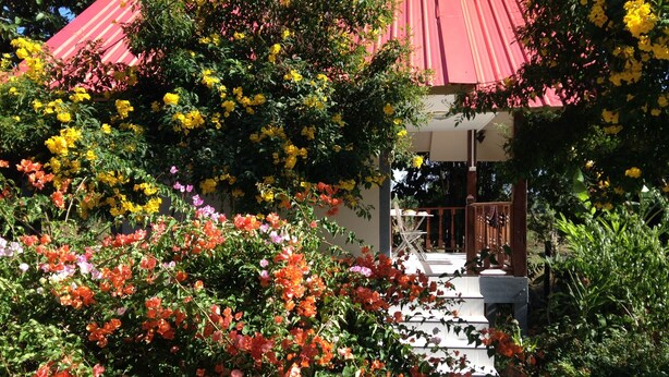 A garden with a variety of flowers and a building with a red roof. - Areeya Resort (Sa Kaeo)