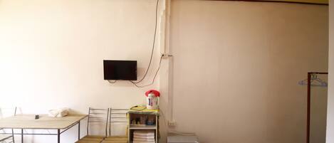 Une chambre avec deux lits, un bureau, une chaise, un téléviseur fixé au mur et un petit réfrigérateur.