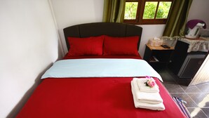 A neatly made bed with red and white bedding, a small bedside table with a lamp, and a window with curtains. - Areeya Resort (Sa Kaeo)
