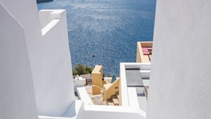 Eine weiße Treppe führt zu einem Balkon mit Blick auf ein Gewässer und das entfernte Land.