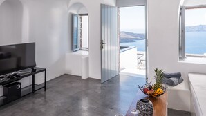 Ein modernes Wohnzimmer mit einem Flachbildfernseher, einem Holztisch mit Obstschale, einem Weinglas und einer Champagnerflasche.