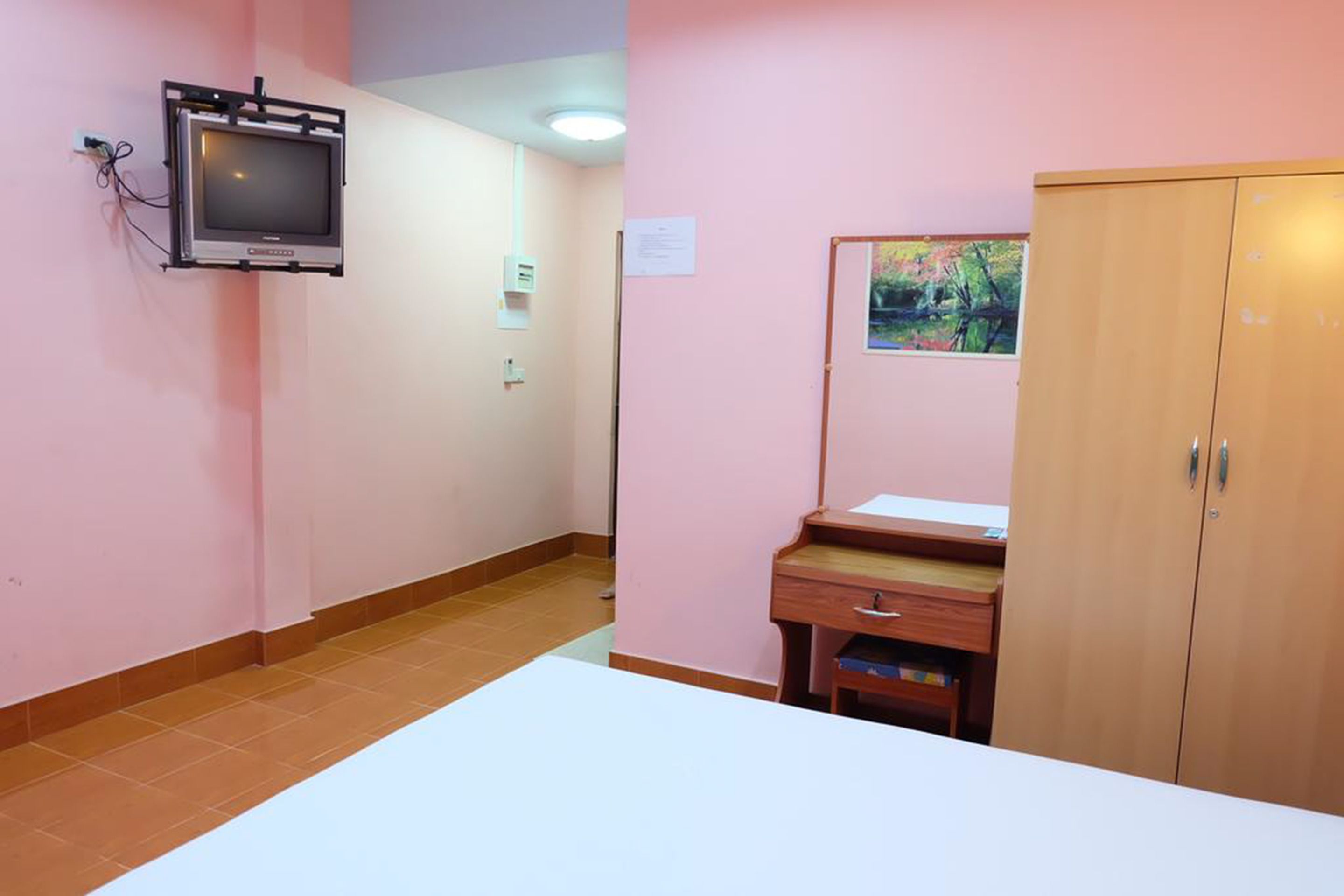 A room with a bed, a desk, a wardrobe, and a mounted television.