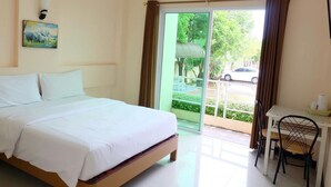 Ein Hotelzimmer mit Bett, Schreibtisch und Stuhl. Ein Fenster mit Vorhängen, eine Klimaanlage und ein Bild an der Wand sind ebenfalls vorhanden.