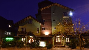 A multi-story hotel with a prominent entrance, a sign indicating a restaurant, and a well-lit facade. - Pousada Belluno (Gramado)
