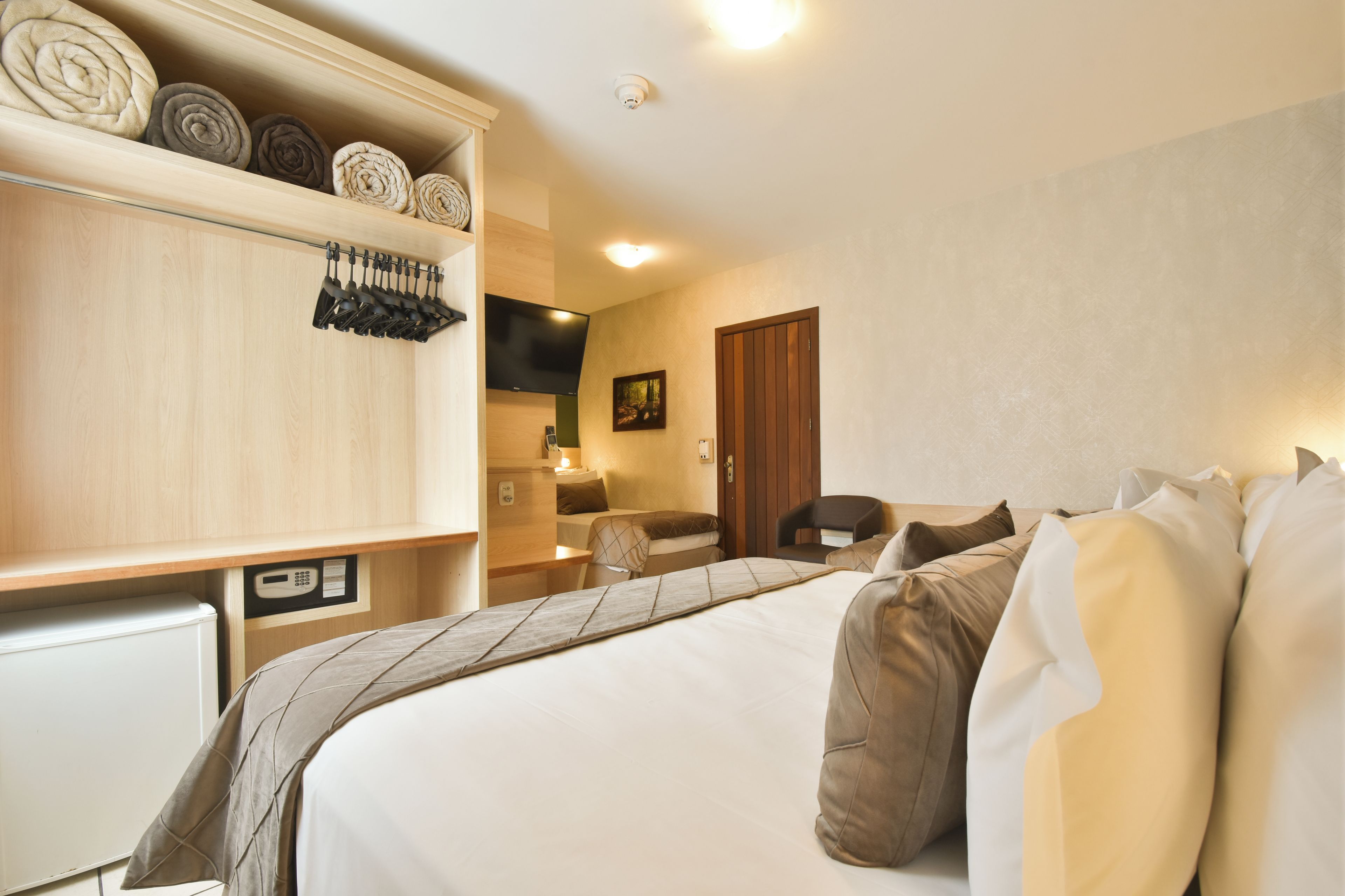 Ein Hotelzimmer mit Bett, Schreibtisch, Stuhl, Fernseher und Kleiderschrank.