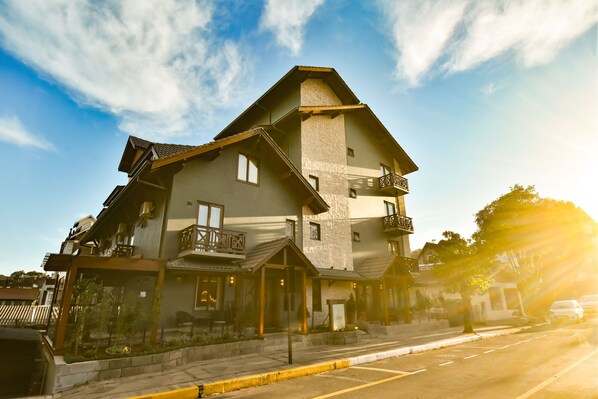A two-story building with a stone facade, multiple balconies, and a corner entrance. - Pousada Belluno (Gramado)