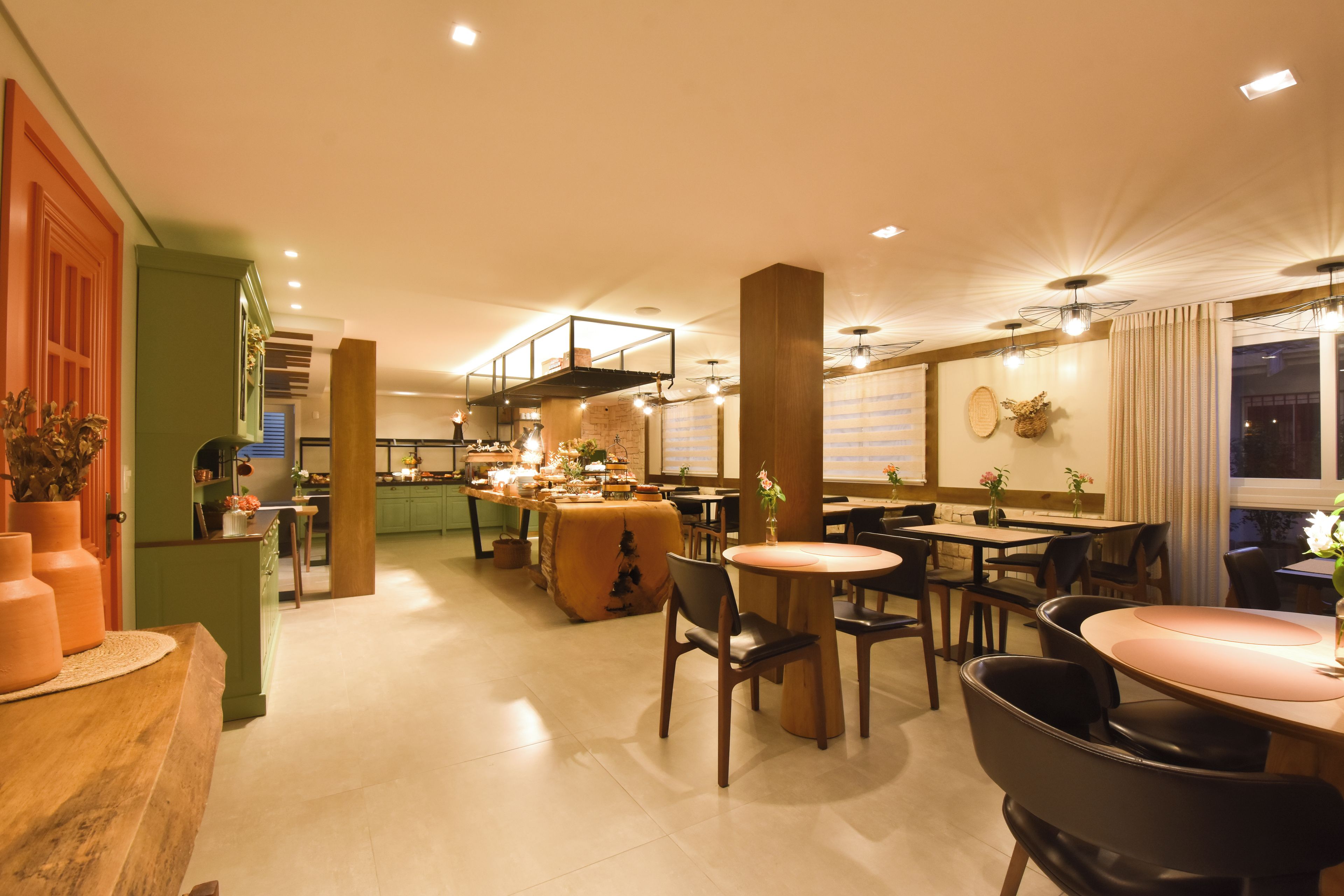 Un restaurant doté d’un bar, de plusieurs espaces de restauration et d’une cuisine visible au fond de la salle.