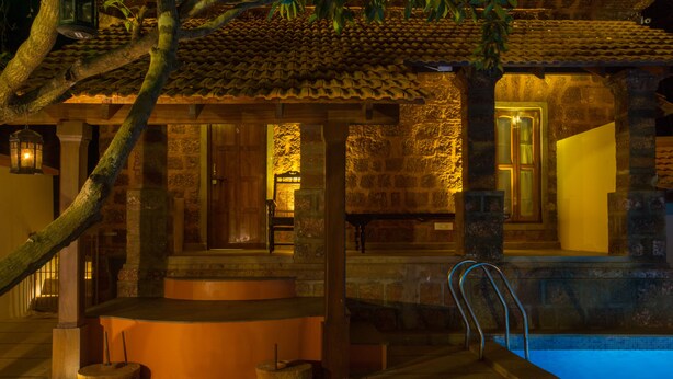 Un edificio tradicional con fachada de piedra, piscina y terraza de madera.