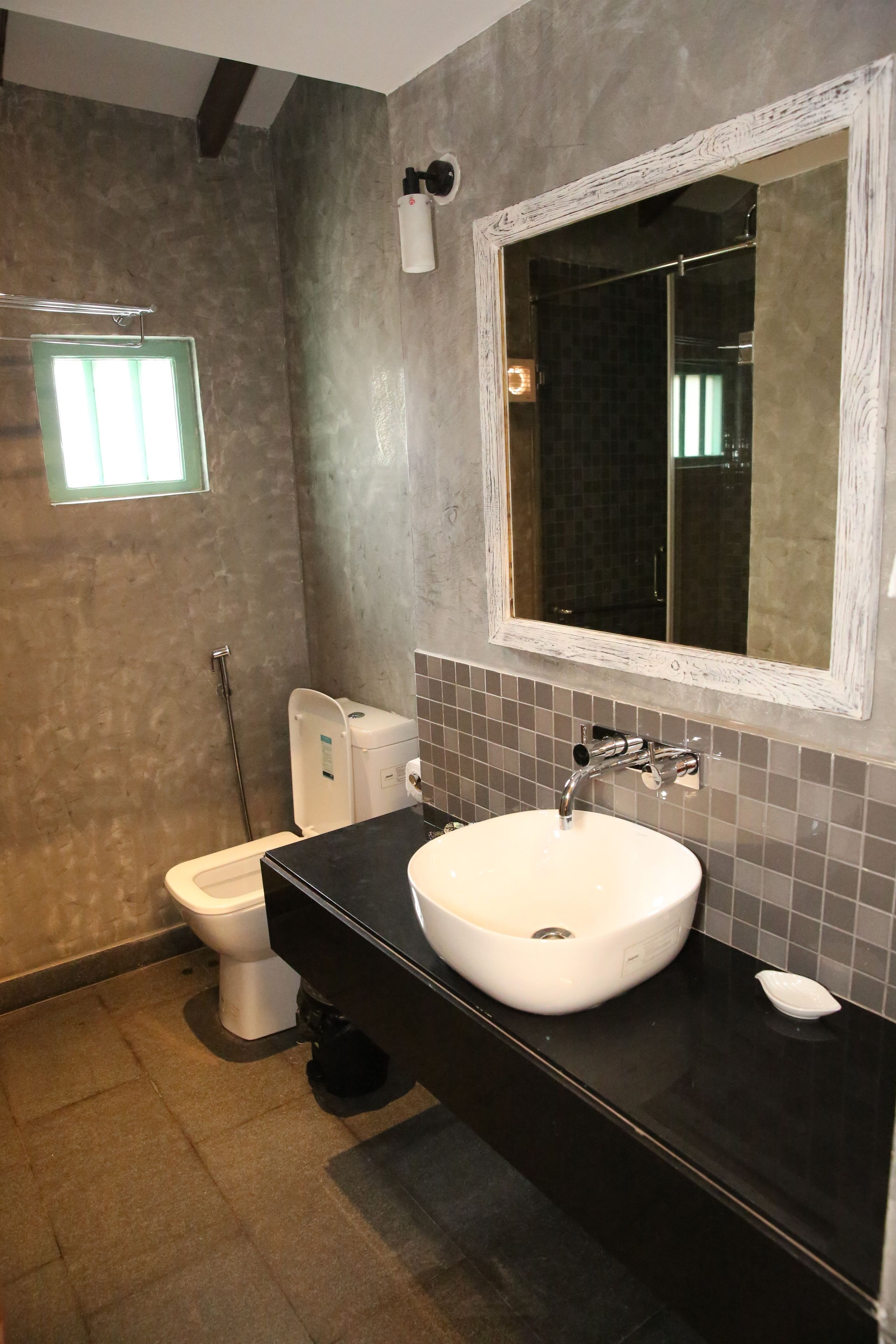 A bathroom with a white sink, a large mirror, and a toilet.