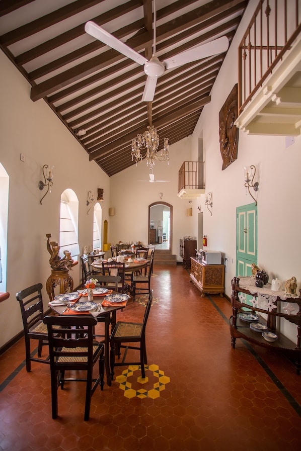 A dining area with wooden tables and chairs, a ceiling fan, and a staircase leading to an upper level.