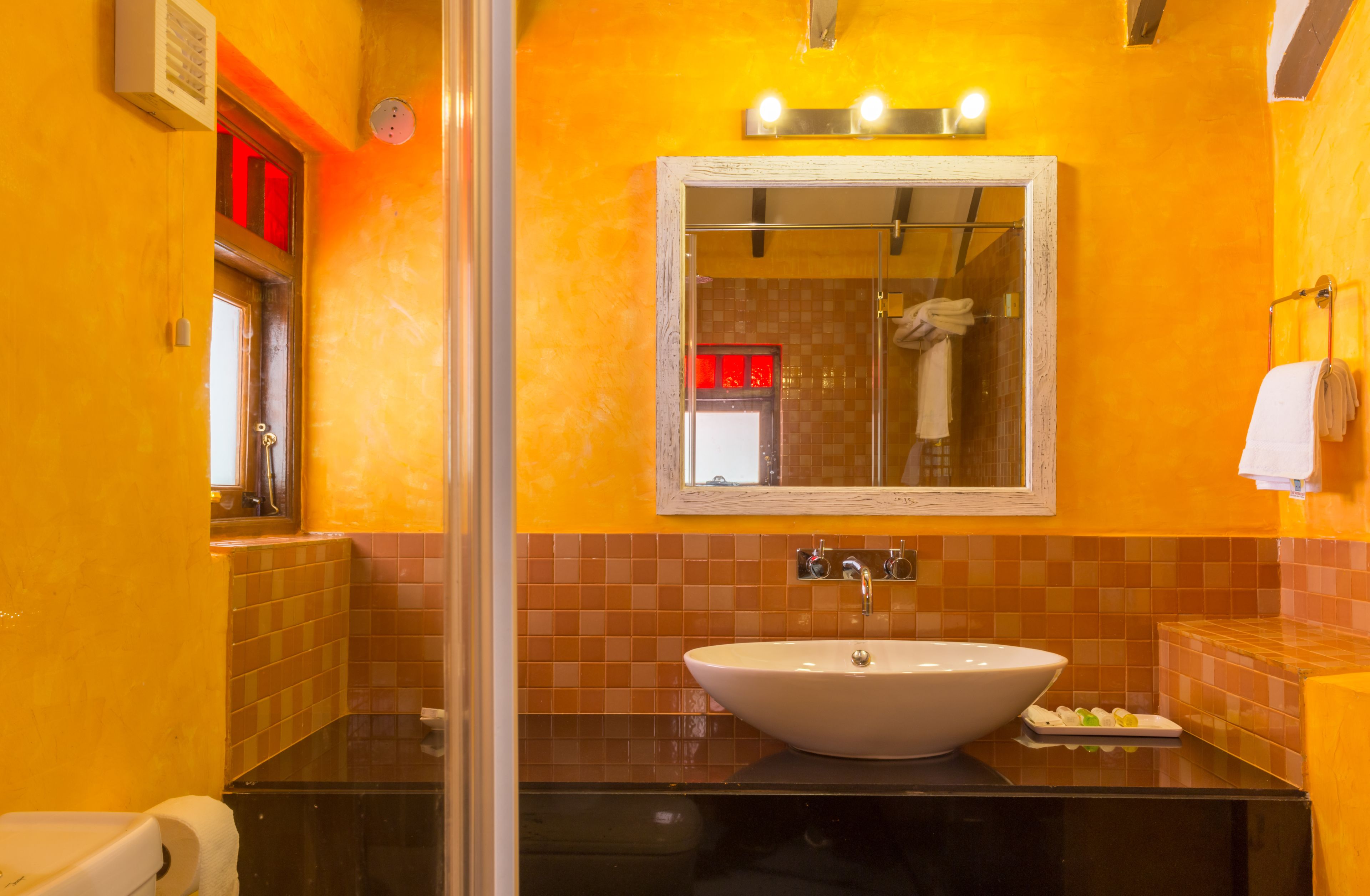 A bathroom with a large white sink, a mirror, and a shower area.