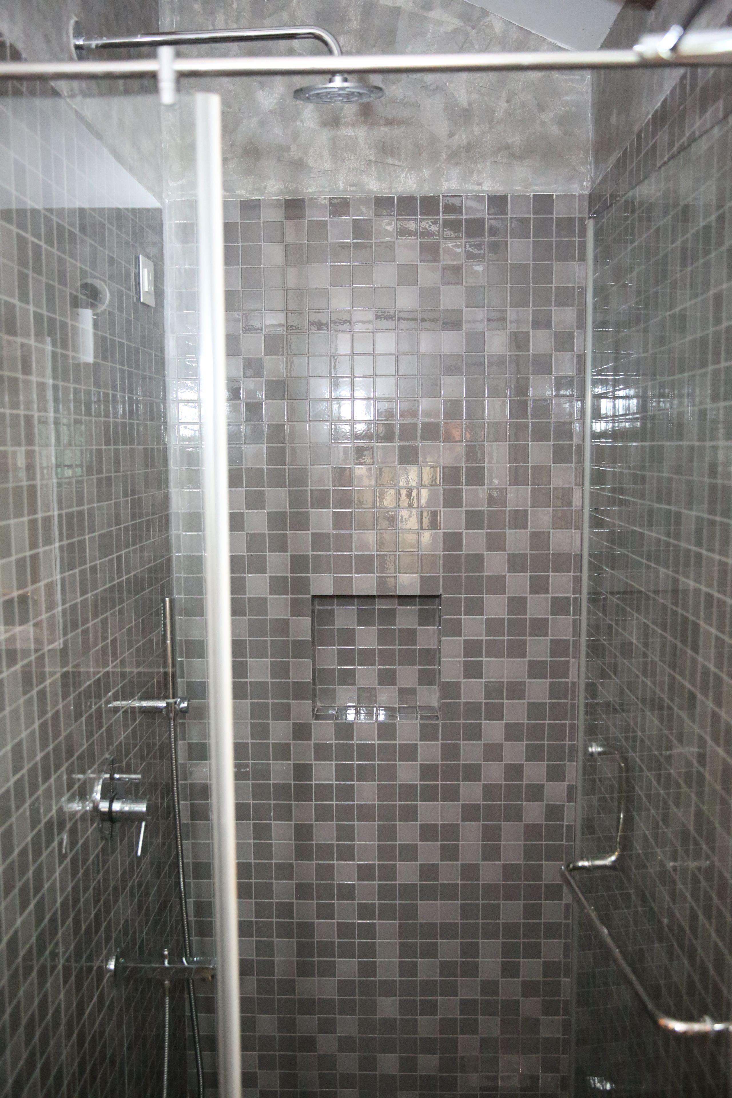 A shower with a glass door, tiled walls, and a metal showerhead.