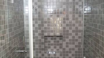 A shower with a glass door, tiled walls, and a metal showerhead.