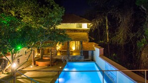Una piscina con terraza de piedra, una escalera y un edificio con tejado de baldosas al fondo.