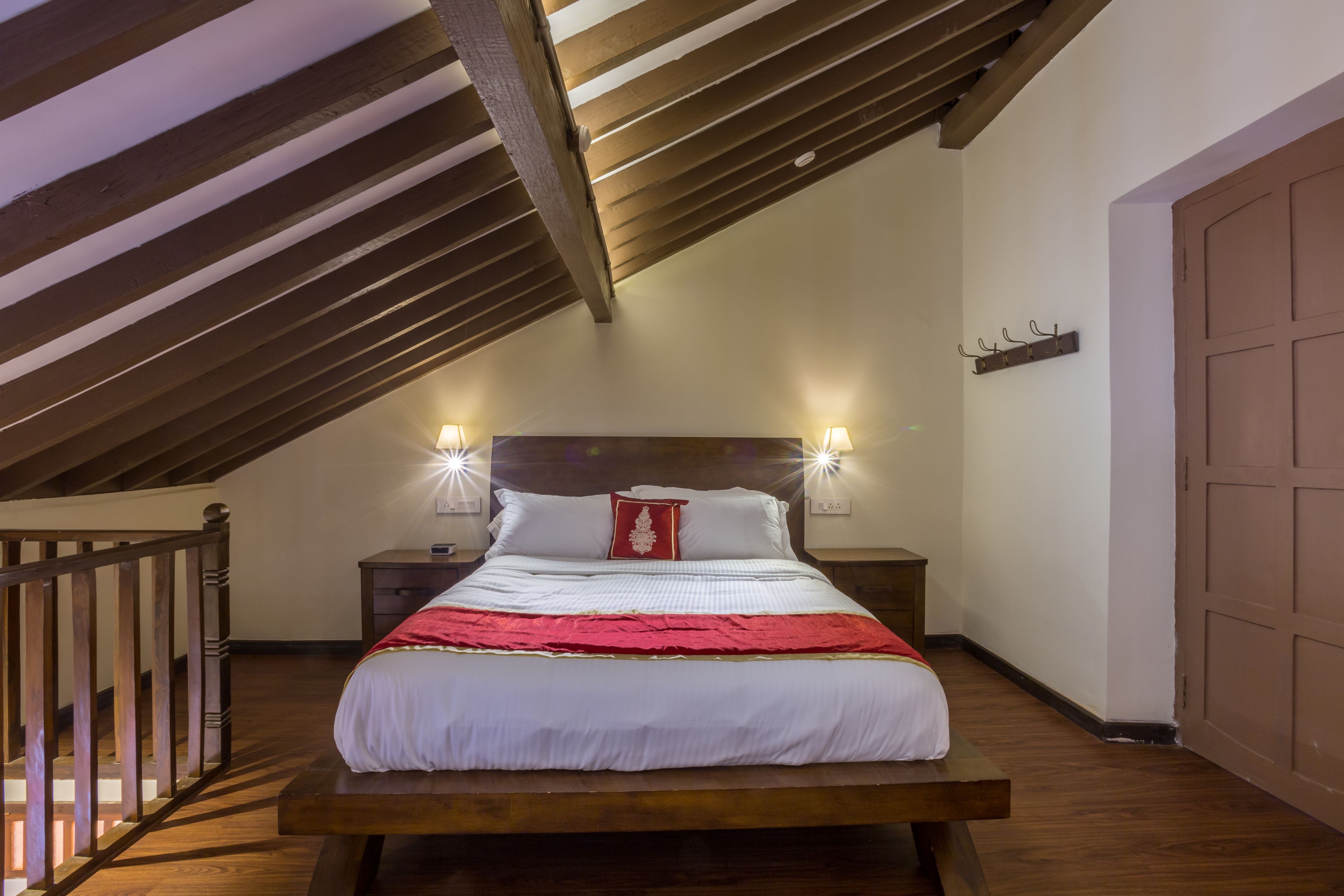 Ein Schlafzimmer mit einem hölzernen Bett, zwei Nachttischlampen und einer roten Tagesdecke.