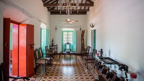 Un pasillo con piso estampado, muebles de madera, un candelabro y un ventilador de techo.