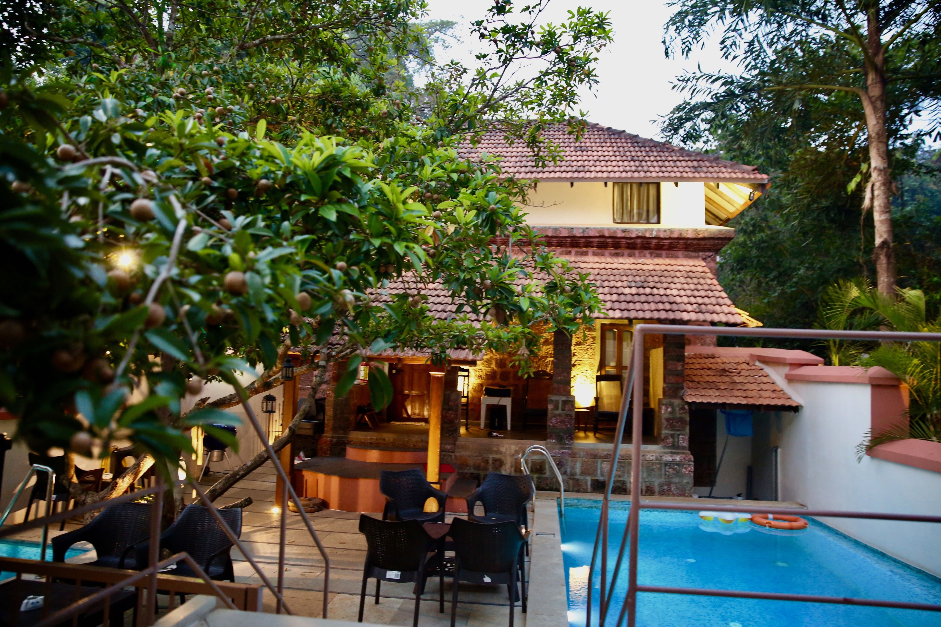 A pool area with lounge chairs, a small pool, and a building with a tiled roof.