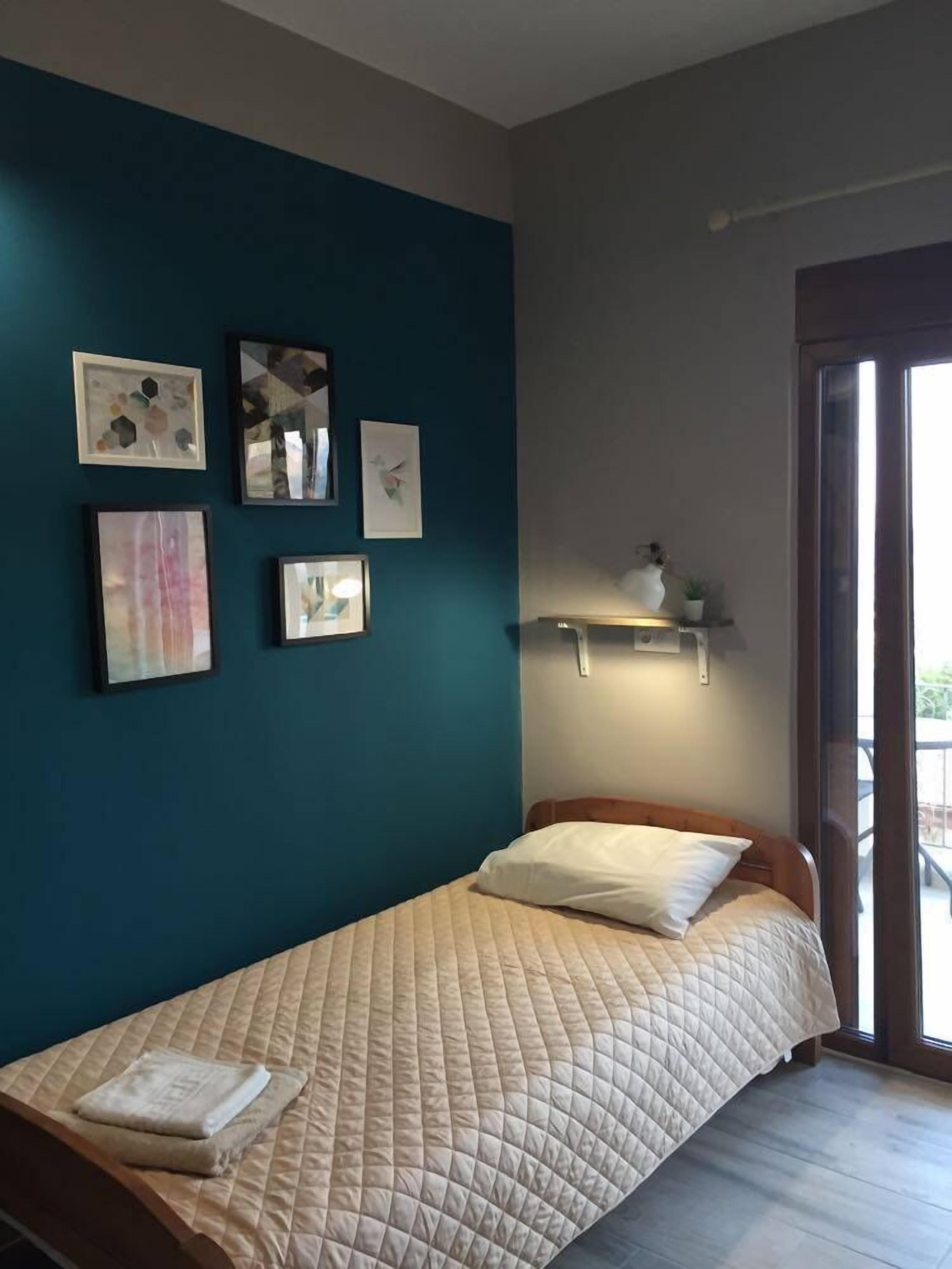 A bedroom with a bed, a window, and wall-mounted shelves.