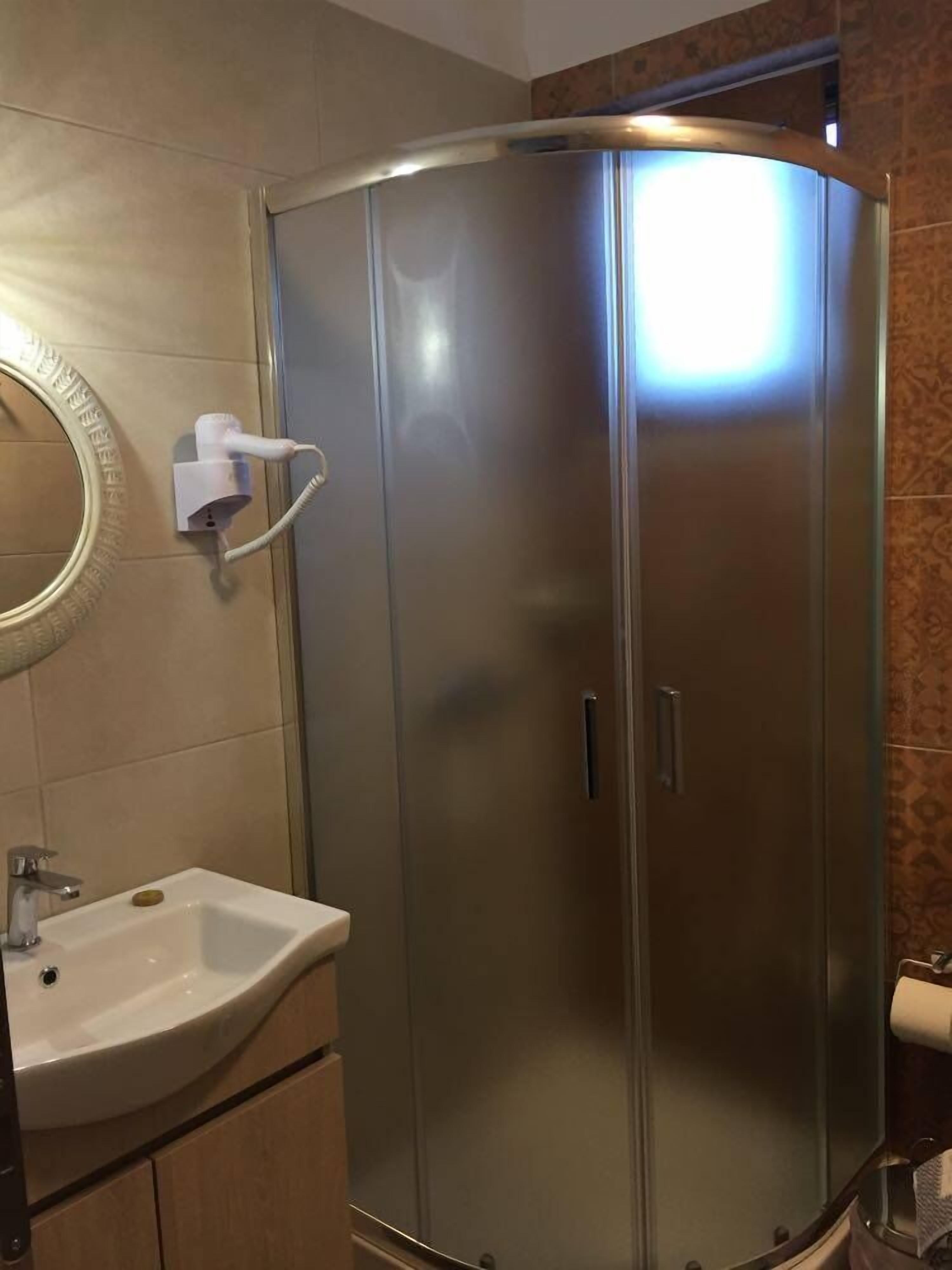 Een badkamer met een douche met stalen wanden, een wastafel en een toilet.
