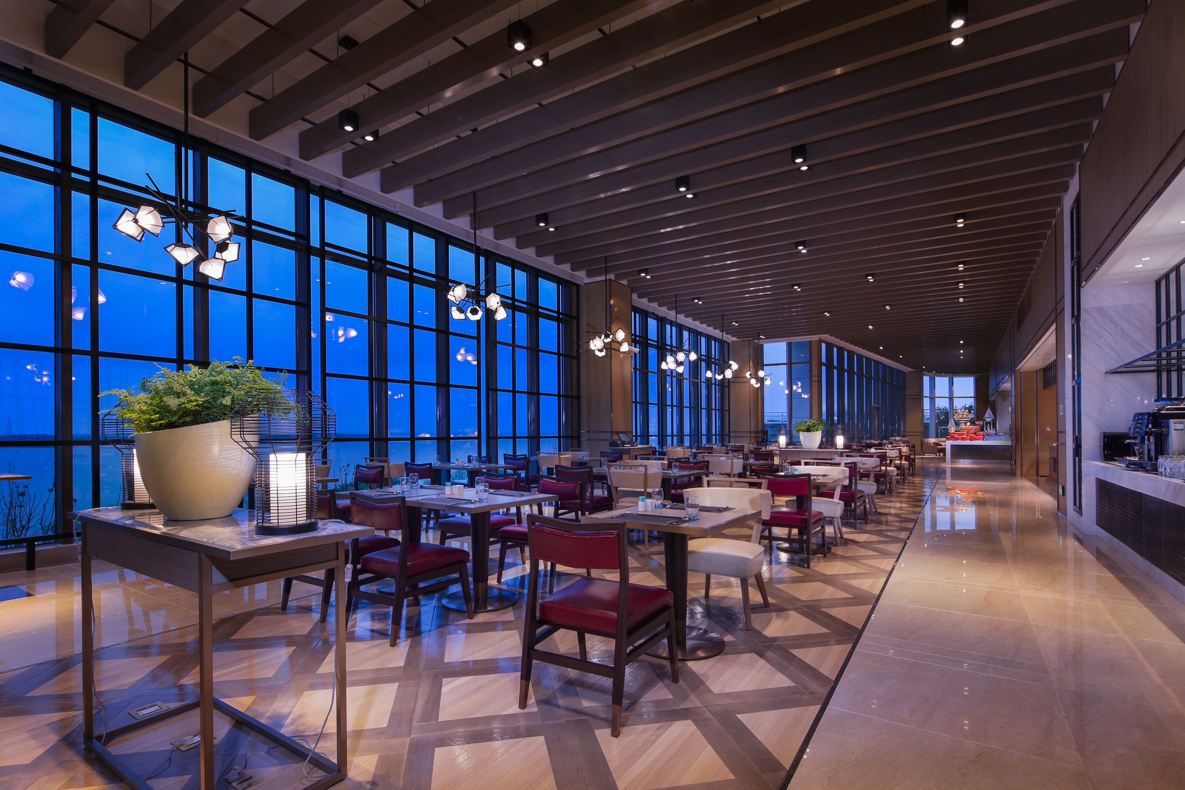 A spacious restaurant with high ceilings, large windows, and modern lighting fixtures.