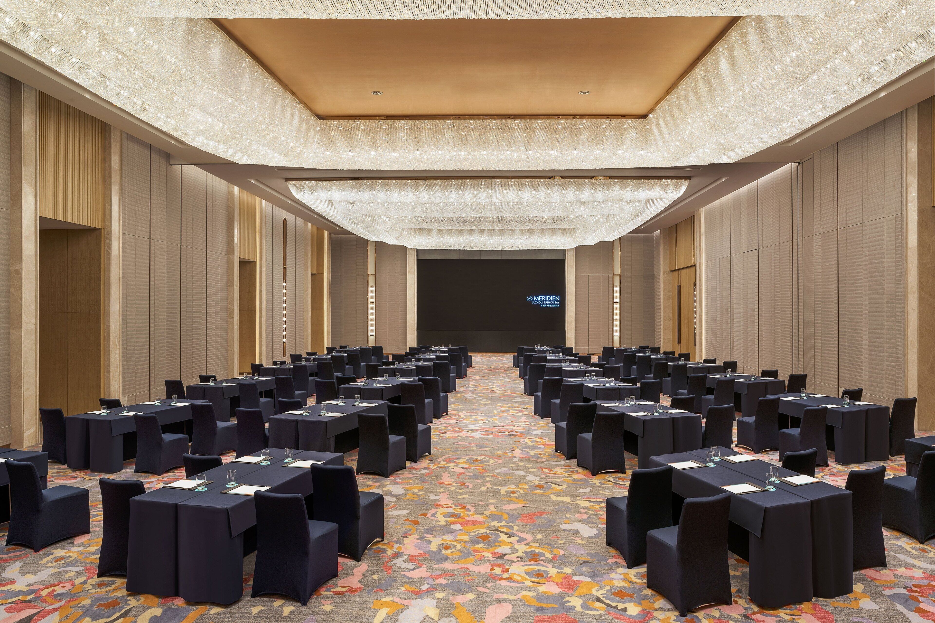 A conference room with rows of tables and chairs, a patterned carpet, and a neutral color scheme.