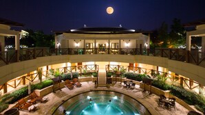 Un hotel con piscina, zona de estar al aire libre y la luna en el cielo.
