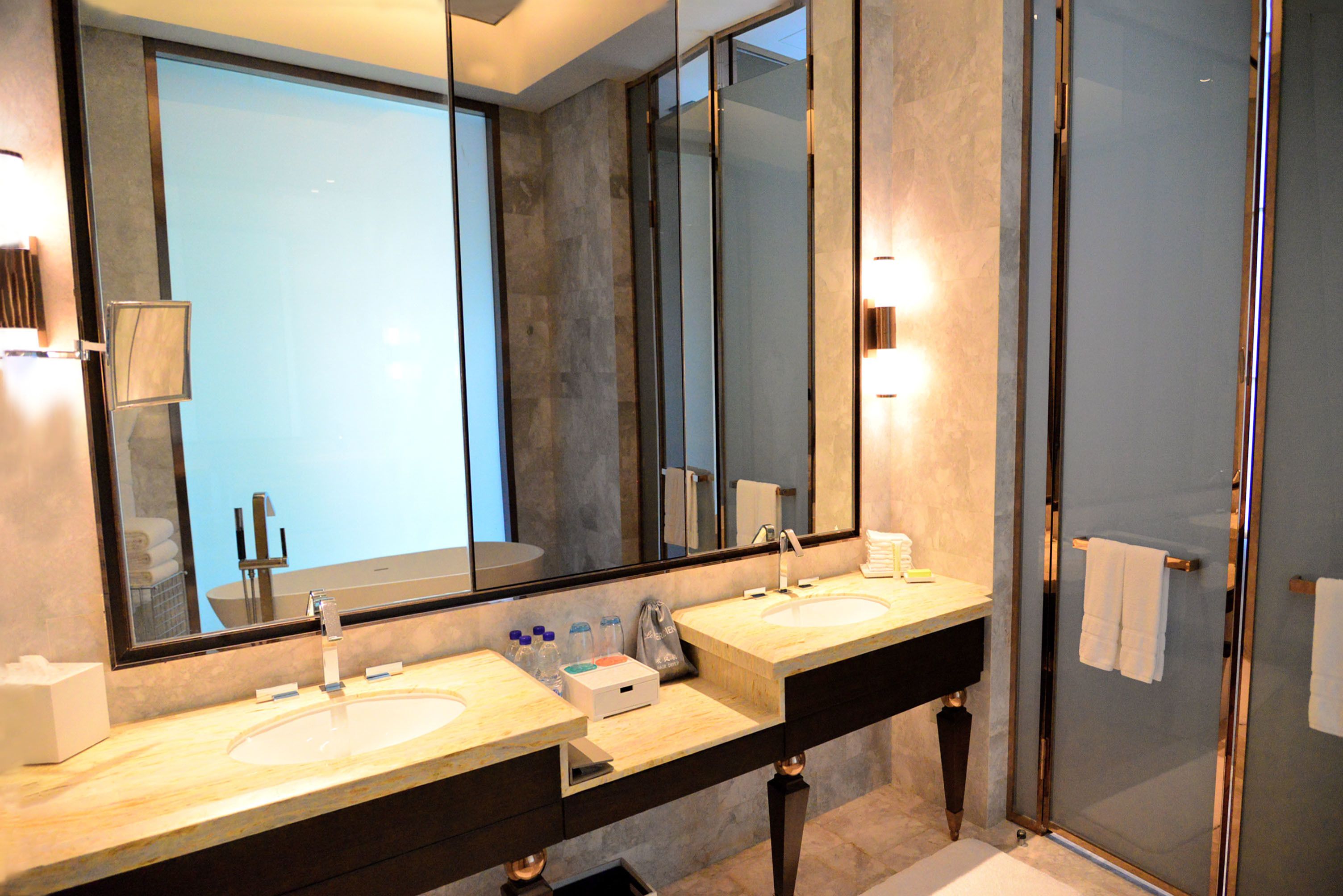 Un baño moderno con dos lavamanos, un espejo grande y una cabina de ducha de vidrio.