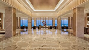 Un vestíbulo amplio con piso pulido, ventanas grandes y una mesa de recepción.