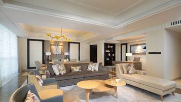 A modern living room with a sofa, armchairs, and a coffee table. There is a television and a lamp on a stand.