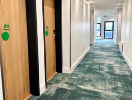 Un pasillo de hotel con puertas de madera identificadas con los números 011 y 010, que conducen a habitaciones.