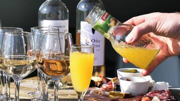 Taula amb vasos de vi i una ampolla de vi, mà abocant una beguda en un vas, i una varietat de formatges i embotits.