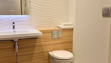 Une salle de bain avec un lavabo blanc, un lambris en bois, des toilettes et un porte-serviettes.