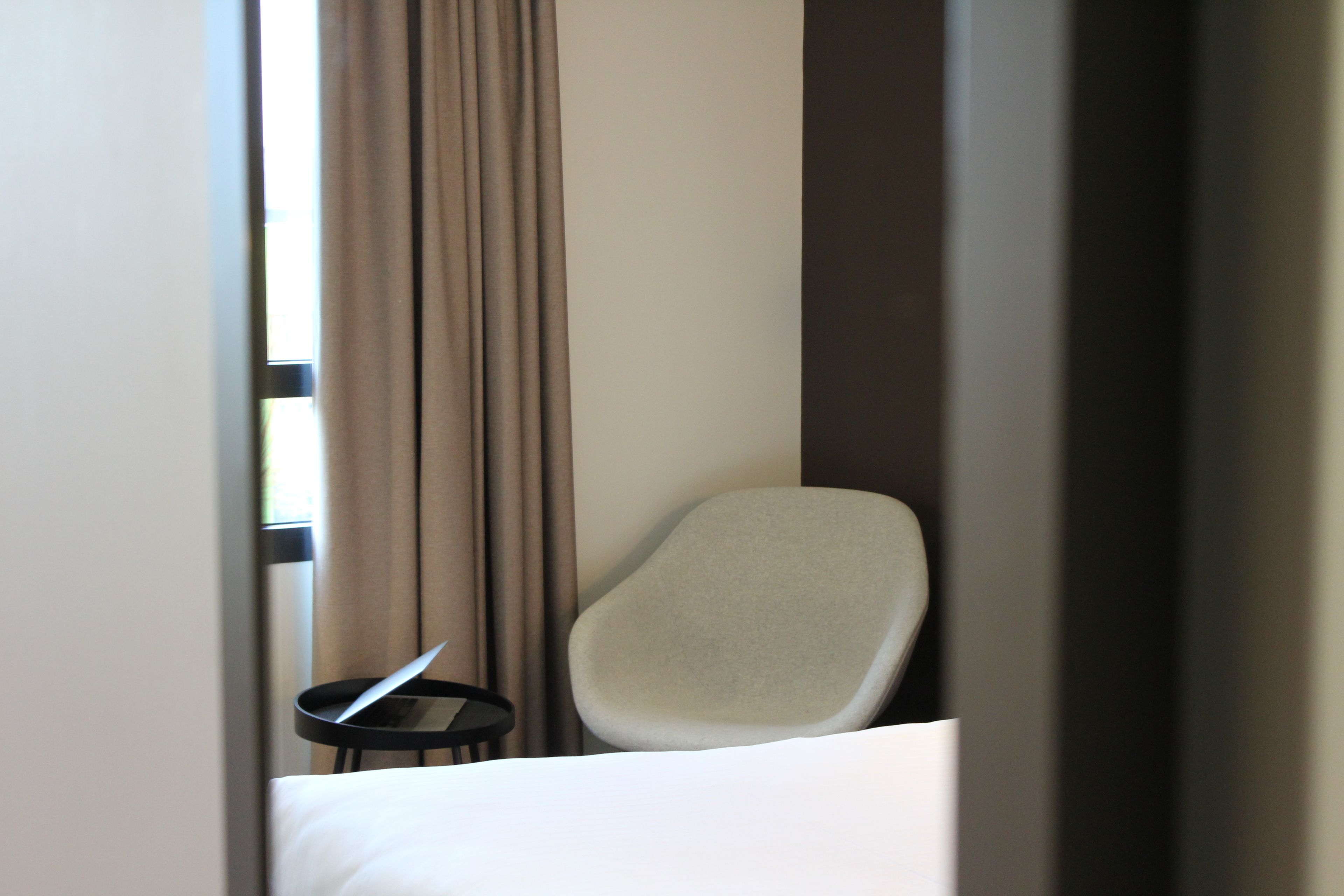 Une chambre d’hôtel avec un lit, une chaise et une petite table sur laquelle se trouve un ordinateur portable.
