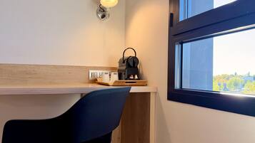 A modern room with a desk, a chair, a coffee machine, and a window with a view.