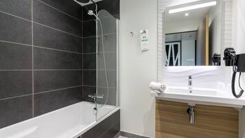 Un baño moderno con bañera, ducha y tocador con espejo.