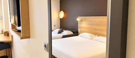A hotel room with a bed, bedside tables, a TV mounted on the wall, and a wall-mounted light fixture.