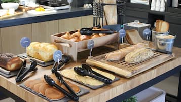 Een buffet met verschillende broden, gebakjes en een koffieapparaat.