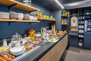 Zona de bufé con diversos alimentos, utensilios y una máquina de café.