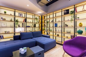 Una sala moderna con un sofá modular, un sillón morado y una mesa de centro negra.