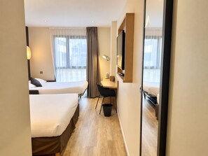 A hotel room with two beds, a desk, a chair, a TV, and a mirror. - Campanile PRIME - Laval Nord (Change)
