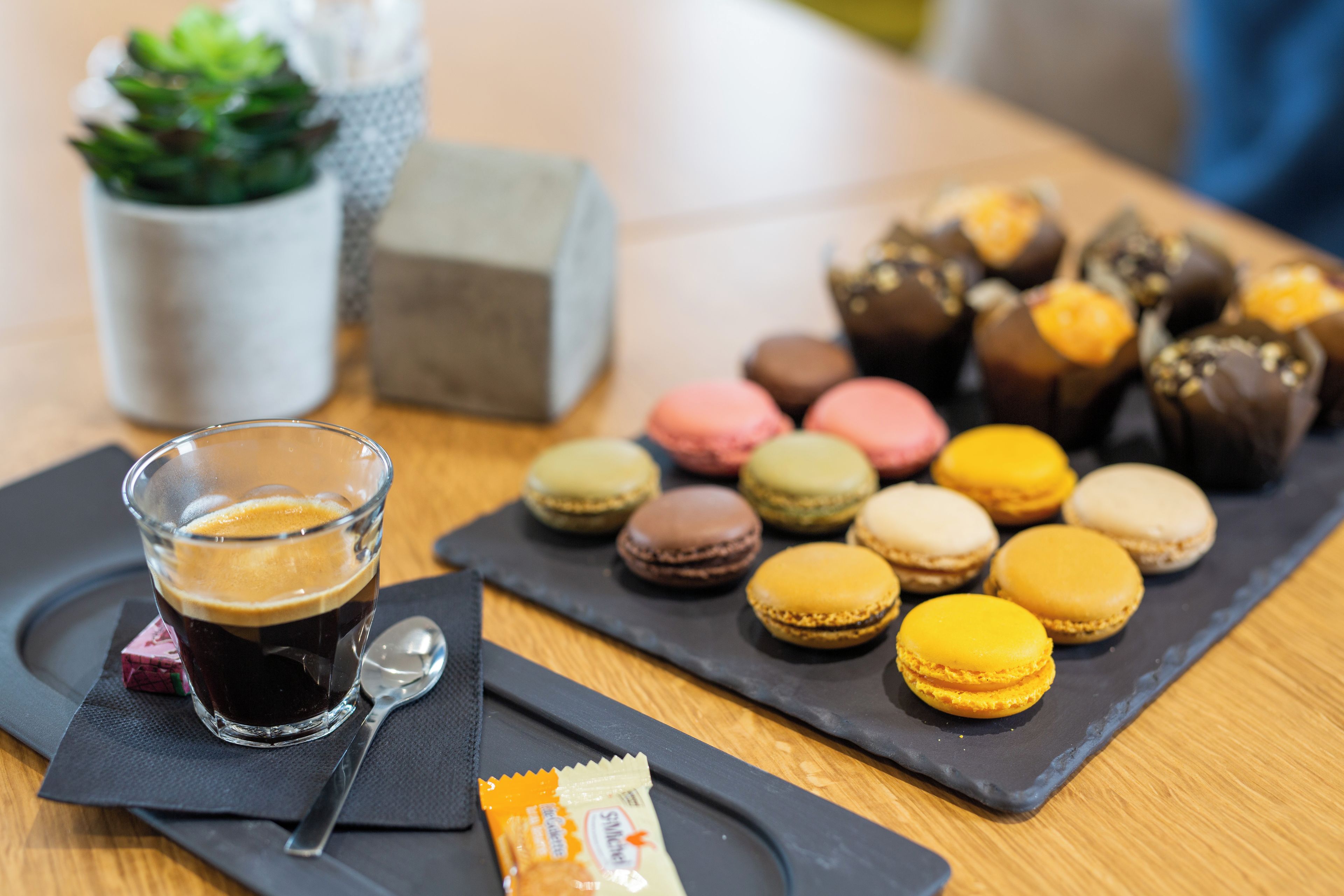 A table with a glass of dark liquid, possibly coffee, and a packet of snacks.