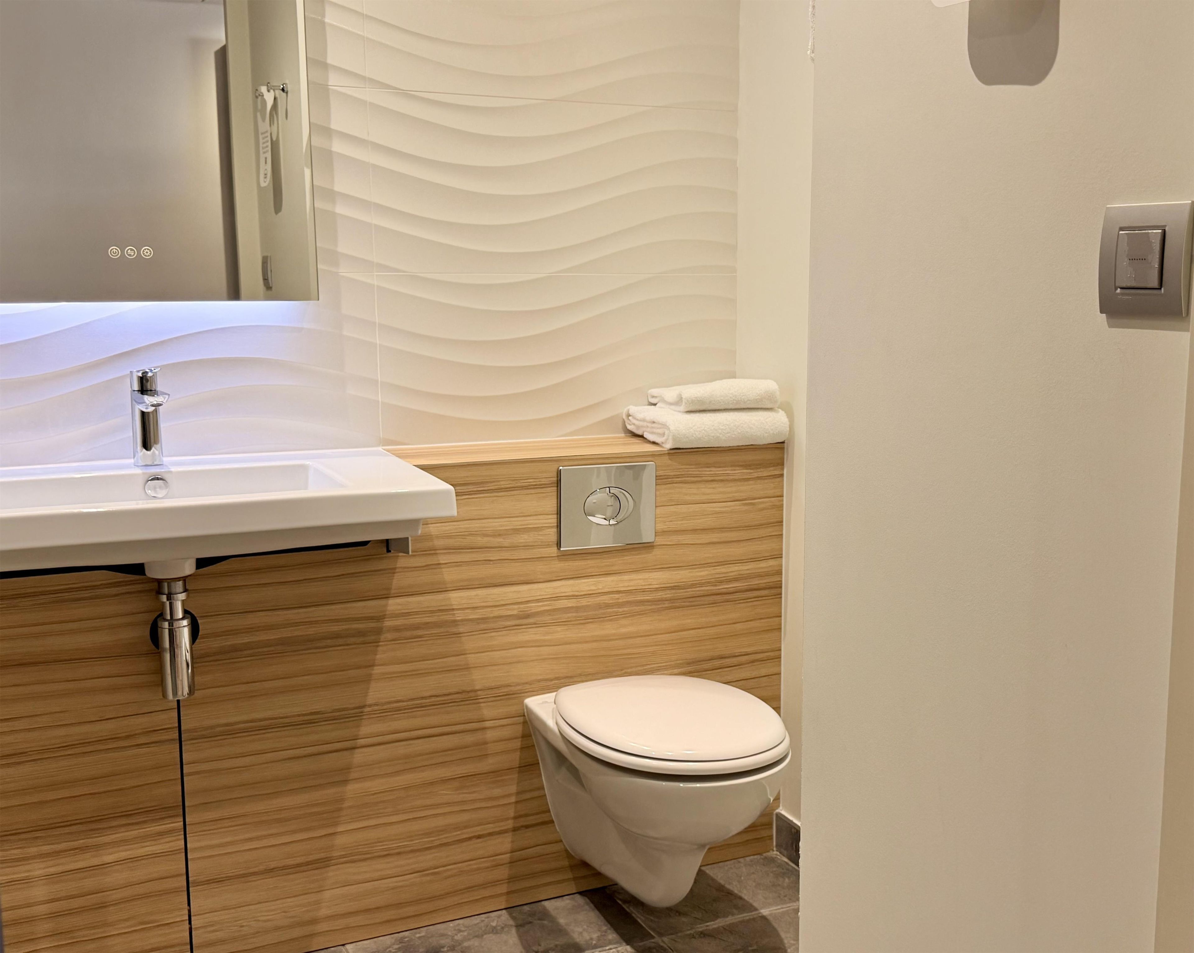 A bathroom with a white sink, a toilet, and a towel rack.