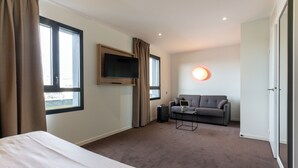Een hotelkamer met een bed, een bank, een televisie en een raam.