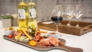 A charcuterie board with various cheeses, meats, and pickles, accompanied by wine glasses and bottles.