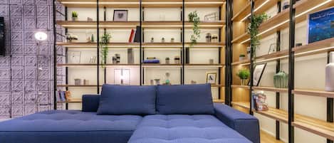 Una sala de estar moderna con un sofá modular, estanterías empotradas con libros y objetos decorativos, y un televisor montado en la pared.