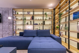 Una sala de estar moderna con un sofá modular, estanterías empotradas con libros y objetos decorativos, y un televisor montado en la pared.